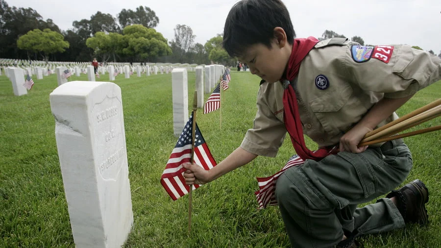 Boy Scout places a flag at a gravesite of a US military veteran © Jonathan Alcorn / Reuters