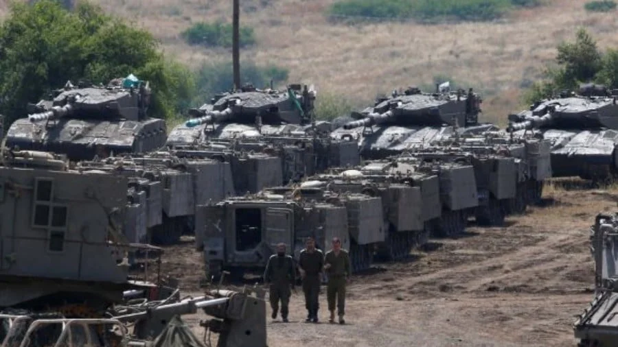 Israeli soldiers walk past armored vehicles in the Israeli-occupied Golan Heights on May 10, 2018. Photo: Reuters/Ronen Zvulun