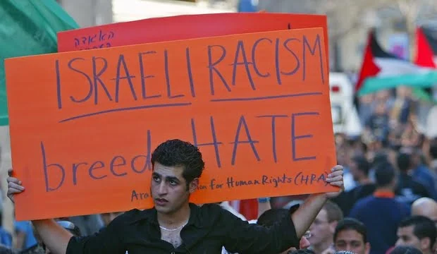 Israeli Arab youth holds sign during demonstration near Roman Catholic Church in Nazareth