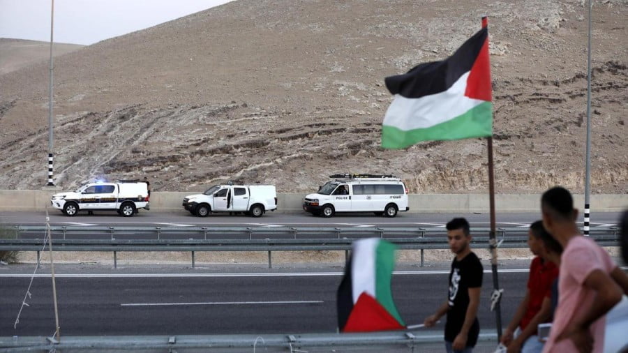 Palestinians hold flags near the Bedouin village of Khan Al Ahmar. EPA/Abed Al Hashlamoun