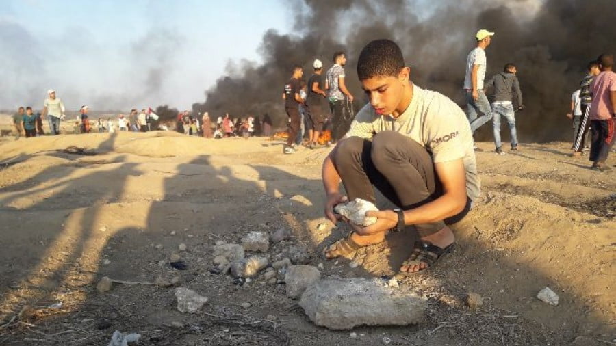 A boy in Gaza gathering rocks to defend against Israeli snipers. (Photo: Abdallah Aljamal, PC)