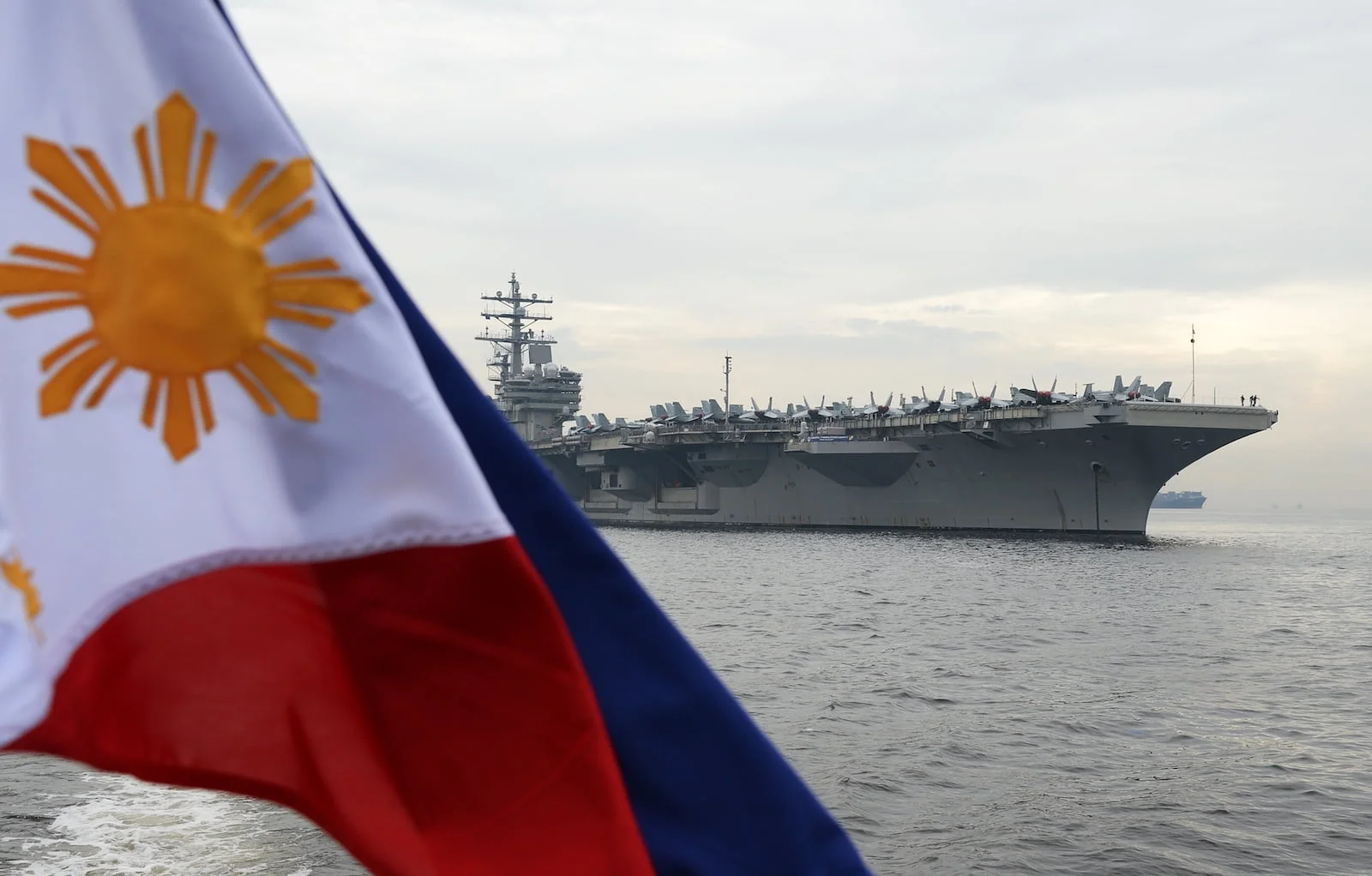 A Philippine flag flutters as the nuclear-powered aircraft carrier USS Ronald Reagan anchors off Manila Bay, June 26, 2018. Photo: AFP/ Ted Aljibe