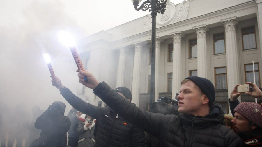 Ukrainian nationalists hold flares during a rally outside parliament on Monday to demand that Kiev break its agreement with Russia on cooperation in the use of the Sea of Azov and the Kerch Strait and impose martial law in the country. The previous day Russia seized three Ukrainian naval ships by force in a strait near Moscow-annexed Crimea. Photo: AFP/ STR / NurPhoto