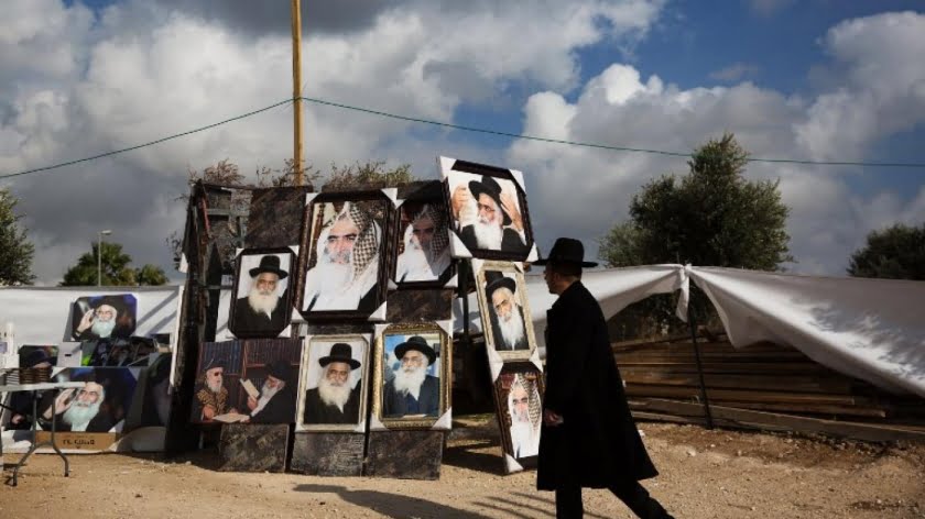 A Jewish man walks past a stall selling portraits of rabbis in the Israeli town of Netivot in 2016 (AFP)