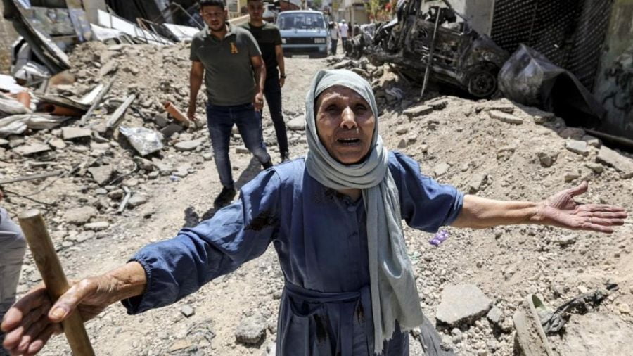 An elderly woman reacts as she stands by the rubble of broken pavement along an alley in Jenin in the occupied West Bank on 5 July 2023 (AFP)